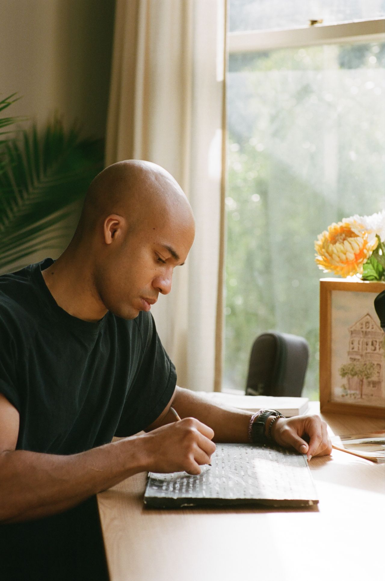 Tucker Bryant writing at his desk by a window
